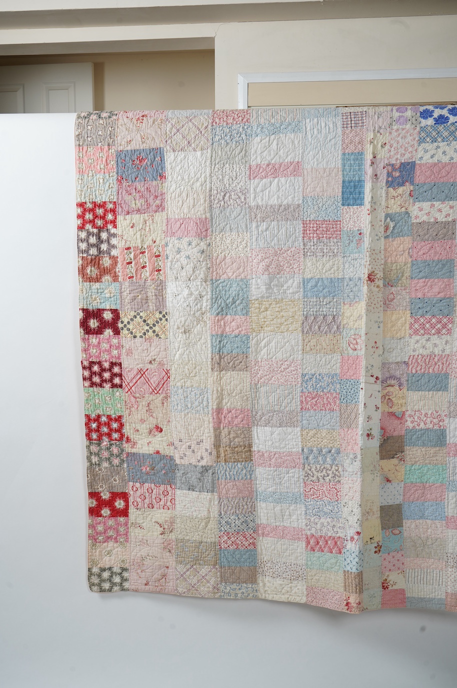 A late 19th early 20th century English cotton ‘scrap bag’ quilt., Made from a large variety of fashionable printed floral, striped and checked cottons of the day, cut into different sized rectangles and squares. Backed w